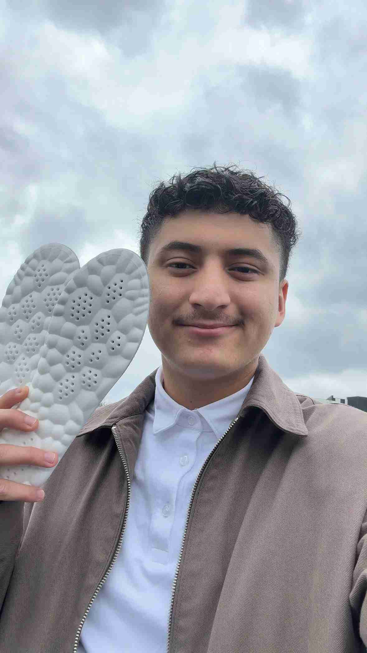 Person holding a textured white object against a cloudy sky