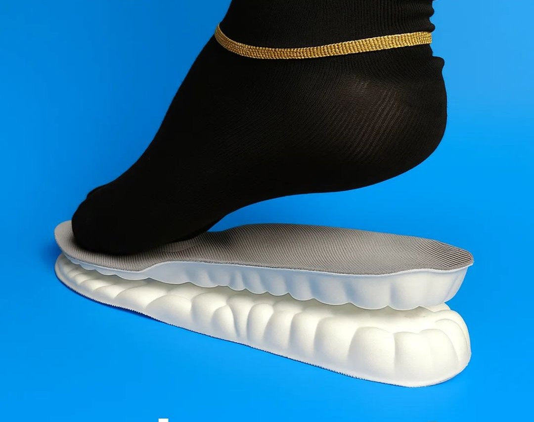 Foot wearing a black sock stepping onto a white orthotic insole against a blue background